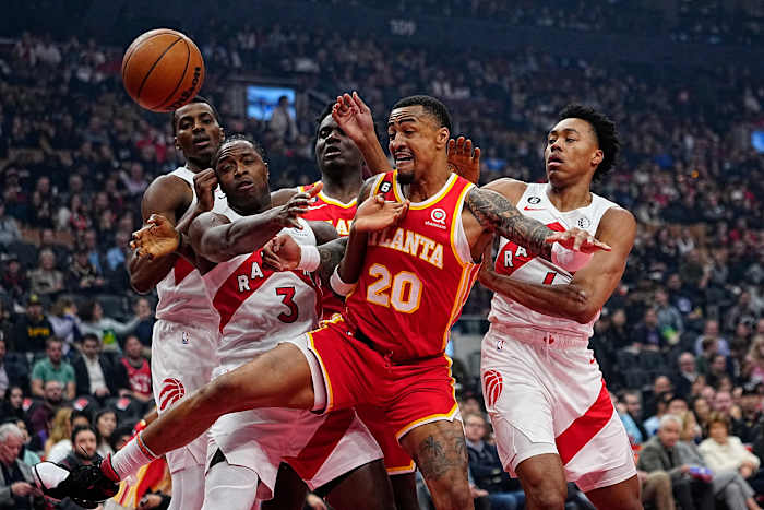 Hawks forward John Collins battles for the ball against Raptors defenders.